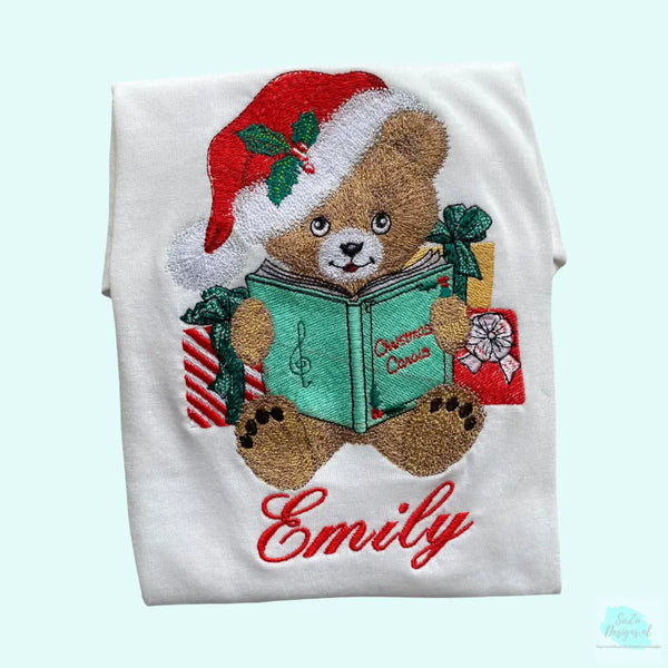 Een geborduurd kindershirt met naam met een geborduurd lief kerst Teddy beertje die uit het boek christmas carols voorleest. Echt een leuk shirt voor de kerstdagen.