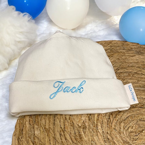 Leuk kraamcadeautje: een handgemaakt baby mutsje in gebroken wit met geborduurde baby naam in divers kleuren. Bijpassend is een handgemaakt gepersonaliseerd baby broekje en handgemaakte baby sokjes verkrijgbaar waarmee u een leuke set cadeau kan doen