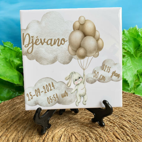Keramiek tegeltje bedrukt met een Konijntje vliegend aan ballonnen. In de wolken worden de naam en de geboortegegevens van de baby bedrukt. De tegel van 15 cm * 15 cm is ook verkrijgbaar in leisteen of een leisteen hart. Super als kraamcadeautje.