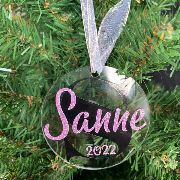 Gepersonaliseerd kerstornament. Gemaakt van een 7cm schijf van acryl. Hierop wordt met zwart vinyl de eerste letter van de naam bedrukt. De naam en het geboorte jaar worden in een kleur vinyl naar keuze gemaakt. Een leuk kerstcadeau.