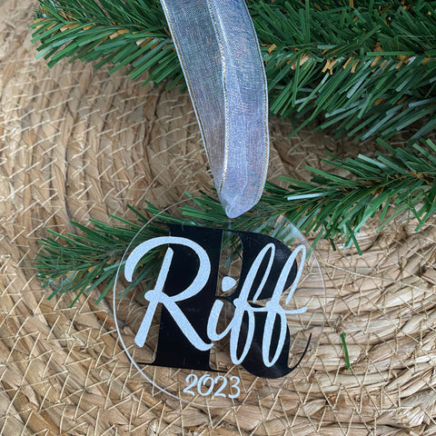 Gepersonaliseerd kerstornament. Gemaakt van een 7cm schijf van acryl. Hierop wordt met zwart vinyl de eerste letter van de naam bedrukt. De naam en het geboorte jaar worden in een kleur vinyl naar keuze gemaakt. Een leuk kerstcadeau.