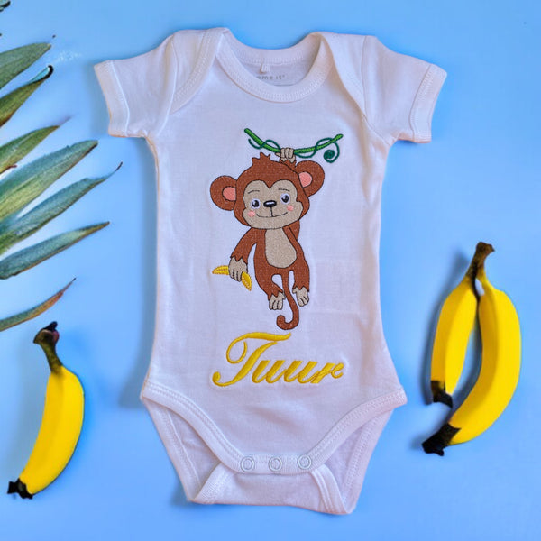 Een gepersonaliseerd rompertje met geborduurde aap met gele banaan en baby naam in geel. Echt een leuk persoonlijk kraamcadeautje. De rompertjes van SaZu Designs zijn verkrijgbaar in wit en zwart, met lange en korte mouw, in de maten 50 tm 68.