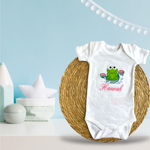 Gepersonaliseerd baby rompertje met geborduurde groene kikker. Een origineel kraamcadeautje. Ook leuk in combinatie met de handgemaakte gepersonaliseerde badcape met kikker.