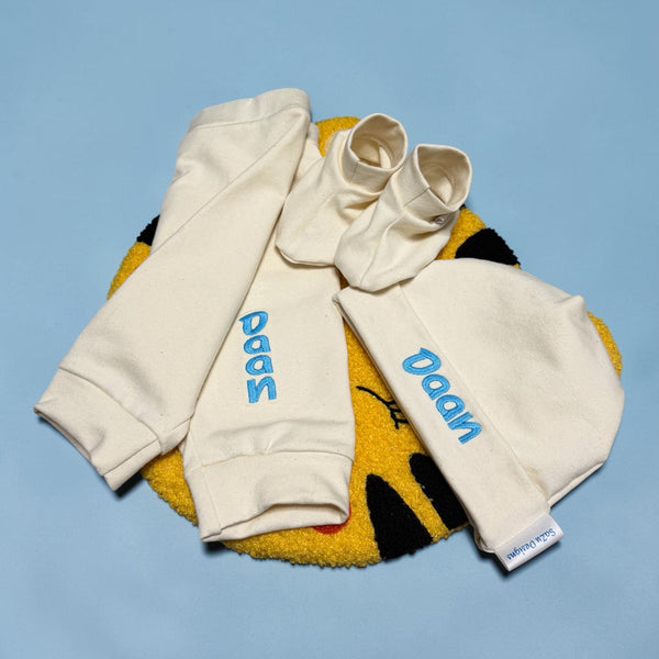 Handgemaakte  kraamcadeau set bestaande uit een gepersonaliseerd baby broekje, een gepersonaliseerd baby mutsje en bijpassende slofjes. Gemaakt van French Terry in de kleur Ivoor. Leuk in combinatie met een bijpassend Rompertje met naam.