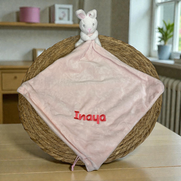 Lief pluche konijntje met een gepersonaliseerde roze deken, geborduurd met naam en geboortedatum – perfect kraamcadeau