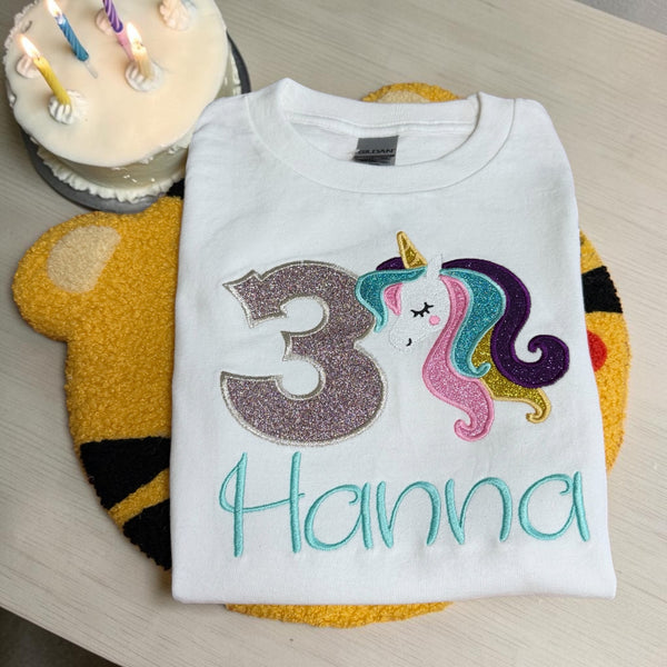 Vrolijk verjaardagsshirt met eenhoorn, glittercijfer en naam. Gepersonaliseerd voor meisjes van 1 t/m 9 jaar. Magisch voor elk verjaardagsfeest!