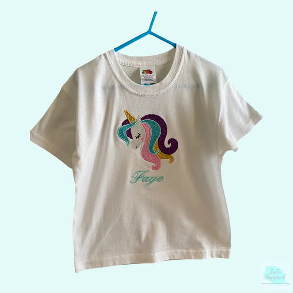 Een gepersonaliseerd meisjes shirt met geborduurde eenhoorn kop met glitter manen in de kleuren roze, aqua, goud en paars. Het shirt is verkrijgbaar in de maten 56 tm 164.