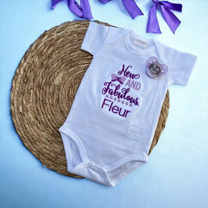 Een geborduurde romper met de tekst " new and fabulous", wordt tevens gepersonaliseerd. Tekst in paars en lila. Een uniek kraamcadeau voor een nieuwe en fabuleuze baby. Romper is 100% katoen.