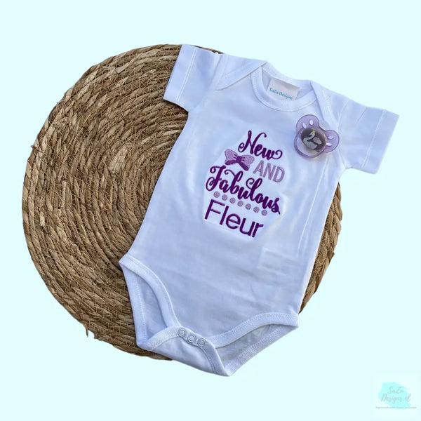 Een geborduurde romper met de tekst " new and fabulous", wordt tevens gepersonaliseerd. Tekst in paars en lila. Een uniek kraamcadeau voor een nieuwe en fabuleuze baby. Romper is 100% katoen.