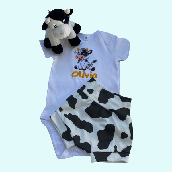 Kraamcadeautje, handgemaakt kort broekje voor baby in koe print samen met de geboorteknuffel koe en het gepersonaliseerde baby; rompertje met geborduurde koe